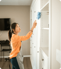 Picture of a woman dusting the cabinets representing standard cleaning.